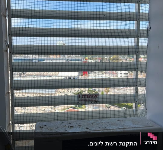 התקנת רשת נגד יונים במסתור כביסה מעל מעבה מזגן